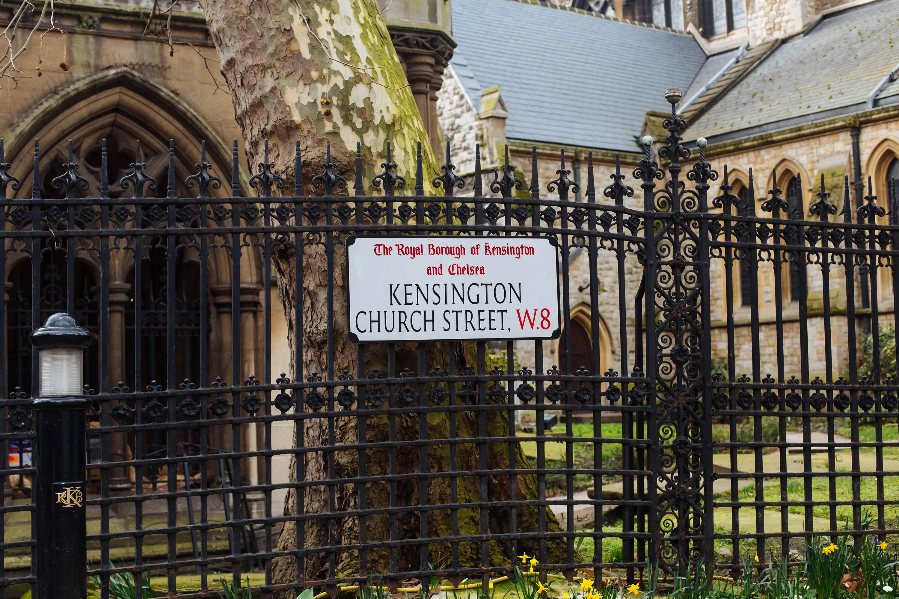 Street sign of Kensington Church Street on railings with a church behind it